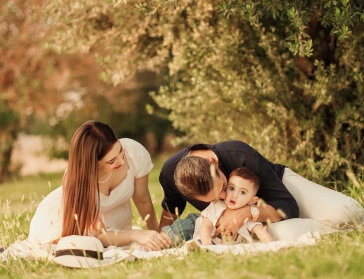 A happy family having a picnic in a lush green park setting during the day.