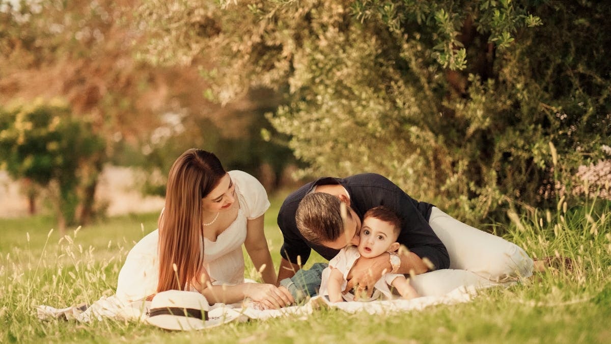 A happy family having a picnic in a lush green park setting during the day.
