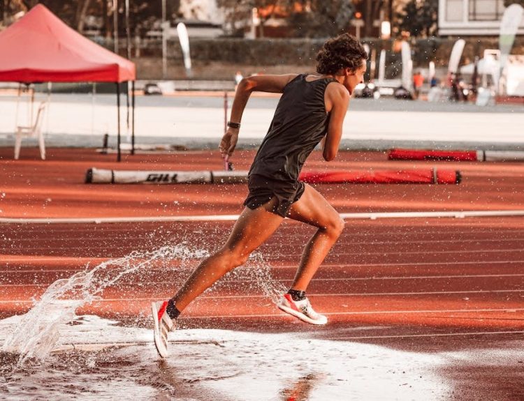Dynamic shot of an athlete sprinting on a wet track, capturing motion and energy.